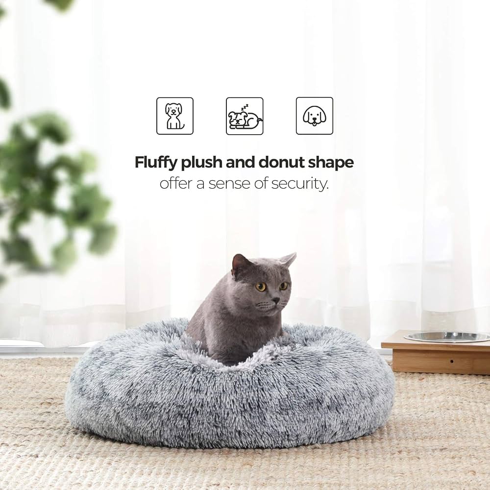 A grey cat sitting in the Feandrea donut bed by a window, showing the fluffy plush and donut shape