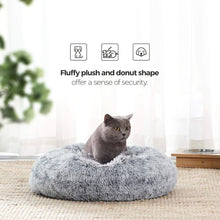 A grey cat sitting in the Feandrea donut bed by a window, showing the fluffy plush and donut shape