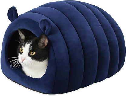 A black and white cat tucked inside the navy velvet hideaway with only its face showing at the entrance